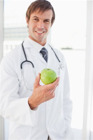simsearch:6109-06006928,k - A surgeon is holding a green apple in front of a window Stock Photo - Premium Royalty-Free, Code: 6109-06006803