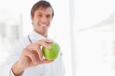 Beautiful green apple held by a surgeon in front a window Stock Photo - Premium Royalty-Free, Code: 6109-06006805