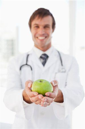 simsearch:6109-06006928,k - A happy doctor is holding a green apple in front of a window Stock Photo - Premium Royalty-Free, Code: 6109-06006808
