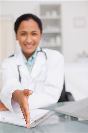 simsearch:6109-06006928,k - Hand extended by a smiling doctor sitting in a medical office Stock Photo - Premium Royalty-Free, Code: 6109-06006901