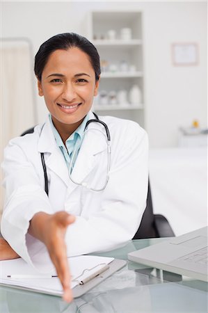 simsearch:6109-06006928,k - Smiling doctor offering a handshake while sitting in her medical office Stock Photo - Premium Royalty-Free, Code: 6109-06006902