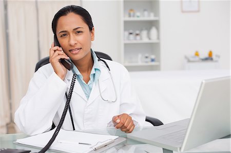 simsearch:6109-06006928,k - Serious doctor looking at the camera while talking on the phone in her medical office Stock Photo - Premium Royalty-Free, Code: 6109-06006907