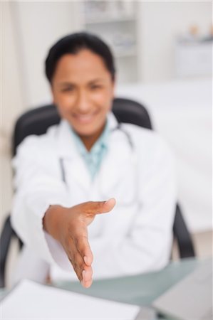 extend - Hand being offered out by a smiling doctor sitting in her office Stock Photo - Premium Royalty-Free, Code: 6109-06006904