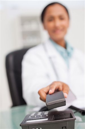 simsearch:6109-06006928,k - Phone being hung up by a doctor sitting in her office Stock Photo - Premium Royalty-Free, Code: 6109-06006915