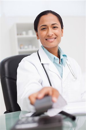 simsearch:6109-06006928,k - Smiling doctor hanging up her  phone while sitting at her desk Stock Photo - Premium Royalty-Free, Code: 6109-06006916