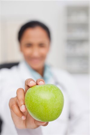 simsearch:6109-06006928,k - Big green apple being held by a doctor sitting at her desk Stock Photo - Premium Royalty-Free, Code: 6109-06006923