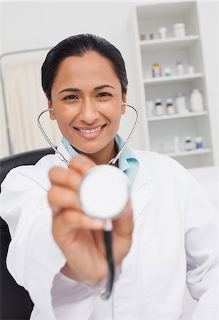 simsearch:6109-06006928,k - Smiling doctor wearing her stethoscope and sitting in her office Stock Photo - Premium Royalty-Free, Code: 6109-06006927