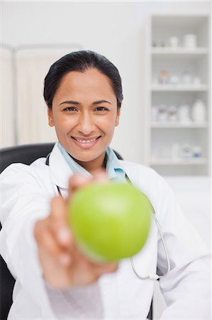 simsearch:6109-06006928,k - Smiling practitioner holding a delicious green apple Stock Photo - Premium Royalty-Free, Code: 6109-06006924