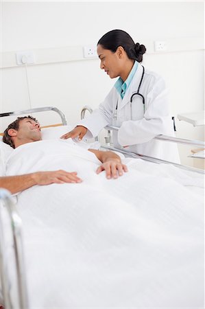doctor nurse and patient men - Serious doctor standing next to the bed of a patient while holding his shoulder Stock Photo - Premium Royalty-Free, Code: 6109-06007062