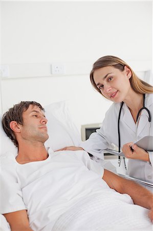 doctor nurse and patient men - Relaxed doctor staring at the camera while staying in a hospital bedroom Stock Photo - Premium Royalty-Free, Code: 6109-06007089