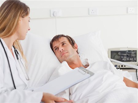 doctor nurse and patient men - Calm patient looking at his nurse while lying in a white hospital bed Stock Photo - Premium Royalty-Free, Code: 6109-06007091