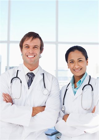 simsearch:6109-06006928,k - Smiling doctors standing side by side with arms crossed while looking at the camera Stock Photo - Premium Royalty-Free, Code: 6109-06007019
