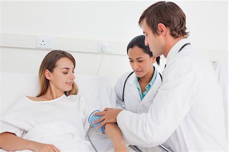 simsearch:6109-06006928,k - Doctor taking the blood pressure of a patient while being accompanied by a nurse Stock Photo - Premium Royalty-Free, Code: 6109-06007036
