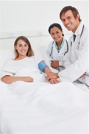 simsearch:6109-06006928,k - Relaxed patient lying in a bed while being accompanied by two smiling surgeons Stock Photo - Premium Royalty-Free, Code: 6109-06007038