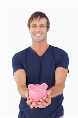 piggy - Smiling man holding a piggy bank against a white background Stock Photo - Premium Royalty-Free, Code: 6109-06007156