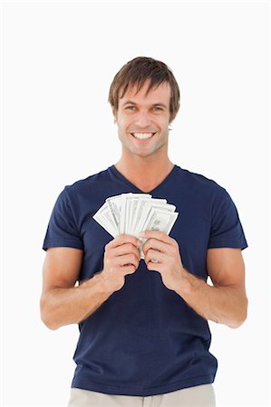 fingers holding - Smiling man holding a fan of bank notes against a white background Stock Photo - Premium Royalty-Free, Code: 6109-06007162