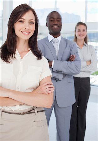 sales team - Two women and a man smile as they stand behind each other with their arms crossed with focus on the first two colleagues Stock Photo - Premium Royalty-Free, Code: 6109-06007198