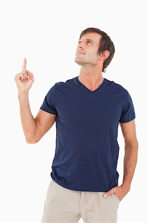 showing - Homme calme, pointant son doigt vers le haut tout en plaçant son autre main dans sa poche Photographie de stock - Premium Libres de Droits, Code: 6109-06007107