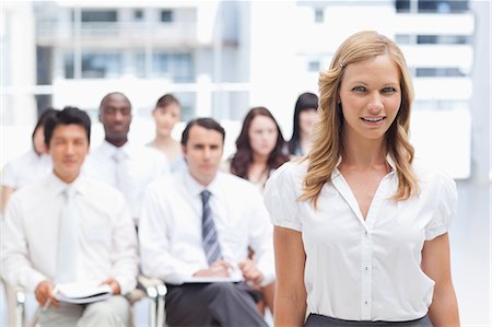 Brunette haired woman looking in front of her while standing with her colleagues behind her Stock Photo - Premium Royalty-Free, Code: 6109-06007263