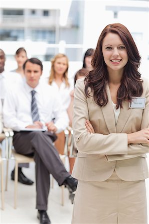 Woman smiling as she crosses her arms while standing in front of her colleagues Stock Photo - Premium Royalty-Free, Code: 6109-06007262