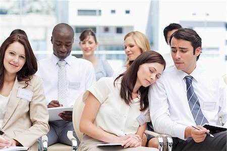 embarrassed women - Woman sleeping oh the shoulder of her colleague while he is looking at her as they sit in a group Stock Photo - Premium Royalty-Free, Code: 6109-06007226