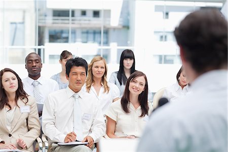 speech - Serious business team looking ahead of them as they watch their colleague giving a speech Stock Photo - Premium Royalty-Free, Code: 6109-06007233