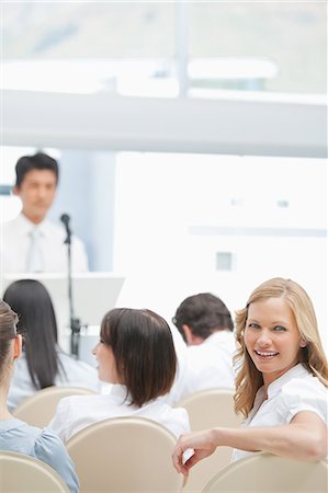 speaker - Close-up of a woman smiling as she looks behind her during a presentation Stock Photo - Premium Royalty-Free, Code: 6109-06007315