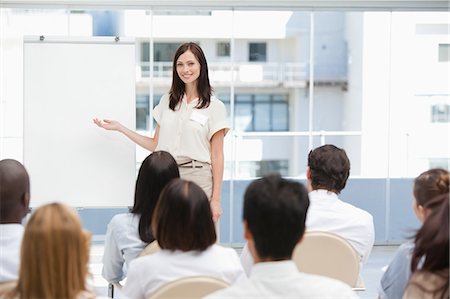 Smiling brunette businesswoman giving a presentation to her colleagues while using a chart Stock Photo - Premium Royalty-Free, Code: 6109-06007331