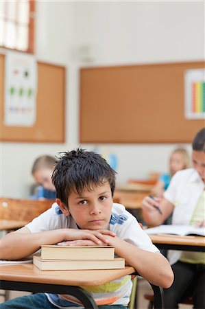 simsearch:6109-06007455,k - Sad looking elementary student leaning on a pile of books Stock Photo - Premium Royalty-Free, Code: 6109-06007450