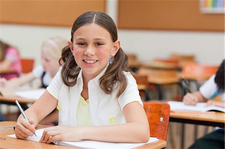 Smiling elementary student sitting at desk Foto de stock - Sin royalties Premium, Código: 6109-06007421