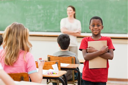 Elementary student standing in class with his exercise book Stock Photo - Premium Royalty-Free, Code: 6109-06007545