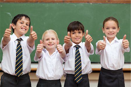 Little schoolchildren in school uniforms giving thumbs up Stock Photo - Premium Royalty-Free, Code: 6109-06007621