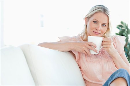 Woman sitting on the sofa with a coffee in her hands Foto de stock - Sin royalties Premium, Código: 6109-06194241