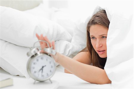 simsearch:6109-06194892,k - Sleepy woman turning off her alarm Foto de stock - Sin royalties Premium, Código: 6109-06194407