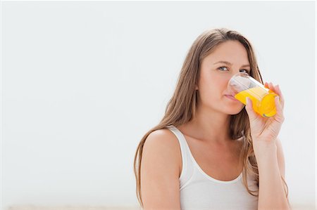 Close-up of a smiling woman drinking a juice Stock Photo - Premium Royalty-Free, Code: 6109-06194435