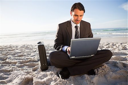 Young businessman sitting cross-legged in front of the ocean Stock Photo - Premium Royalty-Free, Code: 6109-06195352