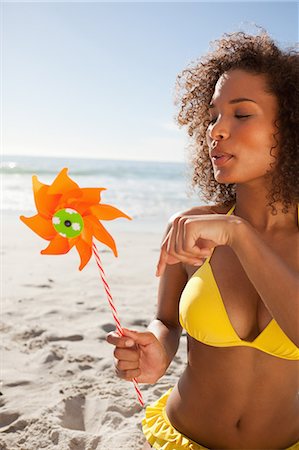 pinwheel - Young attractive woman blowing on an orange pinwheel Stock Photo - Premium Royalty-Free, Code: 6109-06195306