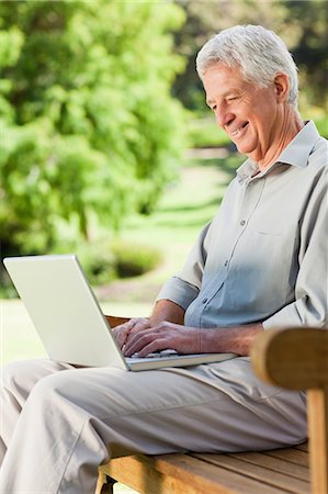 Old man is sitting down with his laptop and smiling Stock Photo - Premium Royalty-Free, Code: 6109-06195441