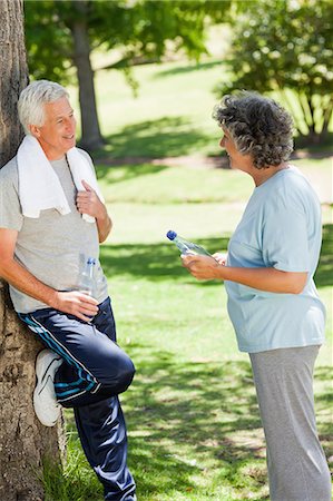 Man in running gear is leaning against a tree talking to a woman Stock Photo - Premium Royalty-Free, Code: 6109-06195450