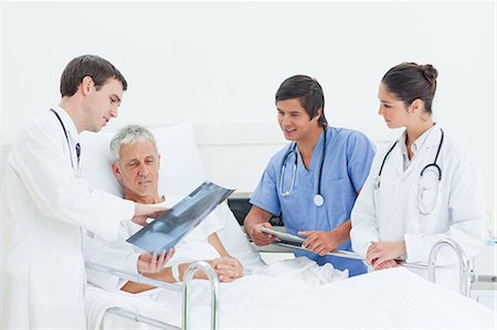 doctor nurse and patient men - Doctor showing a x-ray scan to a patient while being watched by a doctor and a nurse Stock Photo - Premium Royalty-Free, Code: 6109-06195701