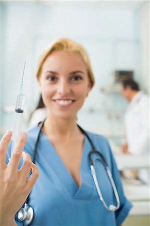 female nurse inject woman - Focus on a blonde nurse holding a syringe Stock Photo - Premium Royalty-Free, Code: 6109-06195941