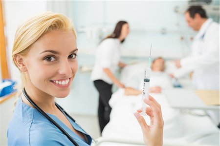female nurse inject woman - Nurse holding a syringe while looking at camera Stock Photo - Premium Royalty-Free, Code: 6109-06195945