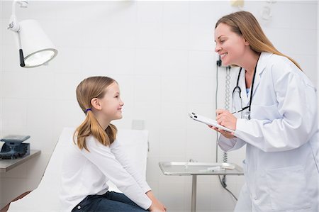 female doctor with child - Smiling doctor talking to a girl sitting on a table Stock Photo - Premium Royalty-Free, Code: 6109-06195976