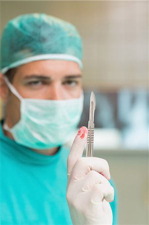 Serious surgeon holding a surgical scalpel Stock Photo - Premium Royalty-Free, Code: 6109-06195900