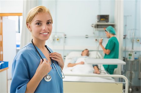 Blonde nurse smiling next to a medical bed Stock Photo - Premium Royalty-Free, Code: 6109-06195914