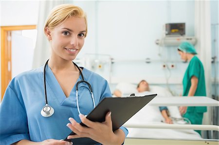 simsearch:6109-06196363,k - Blonde nurse holding a chart while looking at camera Stock Photo - Premium Royalty-Free, Code: 6109-06195922