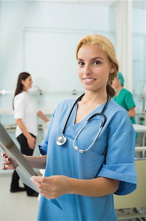 simsearch:6109-06196363,k - Blonde nurse holding a X-ray while looking at camera Stock Photo - Premium Royalty-Free, Code: 6109-06195935