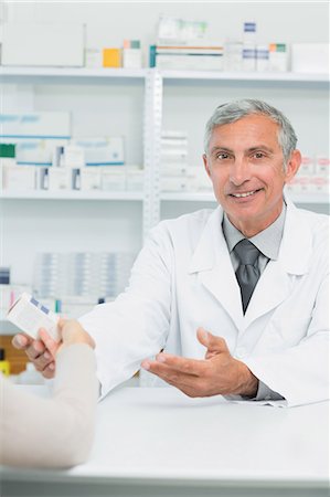 Happy pharmacist giving pills to a customer Stock Photo - Premium Royalty-Free, Code: 6109-06196183