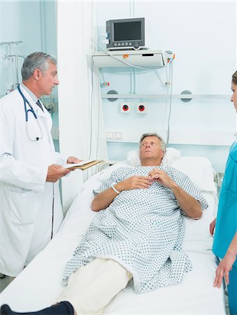 simsearch:6109-06196363,k - Doctor and nurse talking with a patient in a bed ward Stock Photo - Premium Royalty-Free, Code: 6109-06196250