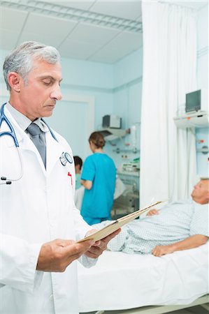 simsearch:6109-06196363,k - Doctor looking at a chart in a bed ward Stock Photo - Premium Royalty-Free, Code: 6109-06196267